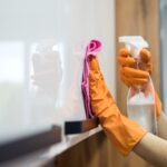 woman-while-cleaning-surface-kitchen-desk-with-sponge-her-rubber-gloves-housework-min
